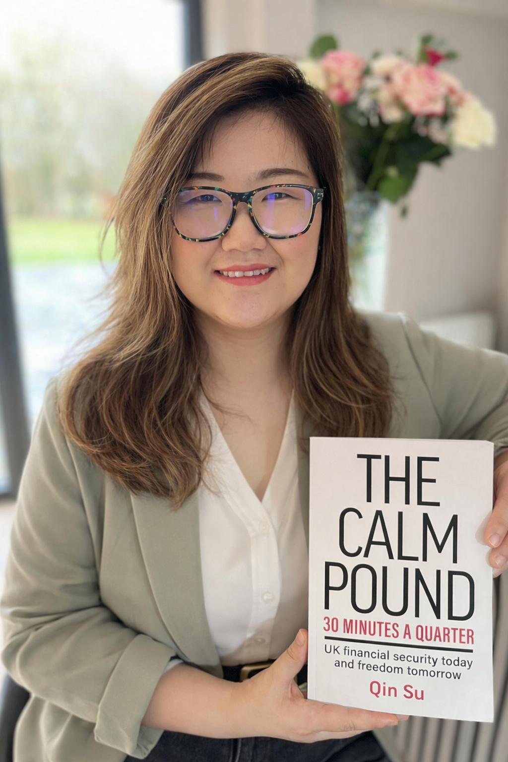 Qin Su - Financial Coach and Author of The Calm Pound Qin Su, author and financial coach, smiling in professional headshot holding her book "the Calm Pound"